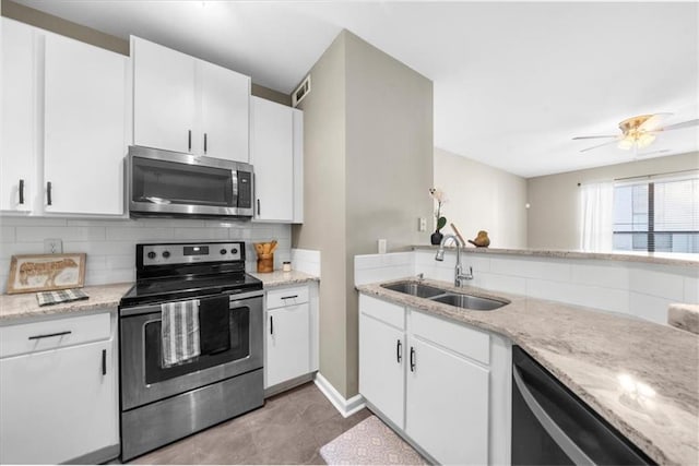 kitchen featuring sink, tasteful backsplash, light stone counters, appliances with stainless steel finishes, and white cabinets