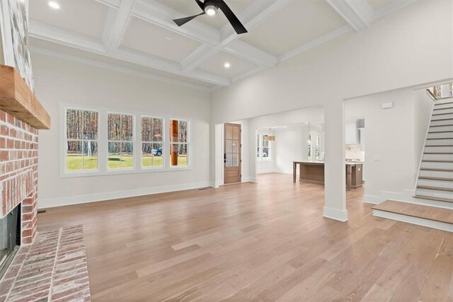 unfurnished living room featuring beamed ceiling, ceiling fan, light hardwood / wood-style floors, and a fireplace