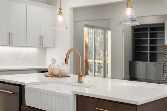 kitchen with backsplash, sink, white cabinets, and decorative light fixtures