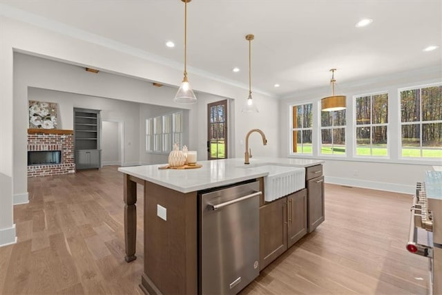 kitchen featuring a brick fireplace, sink, pendant lighting, a center island with sink, and dishwasher