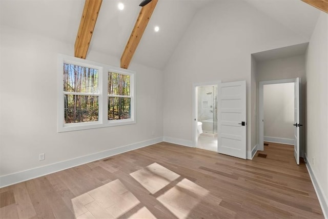 unfurnished bedroom featuring high vaulted ceiling, light hardwood / wood-style floors, beam ceiling, and connected bathroom