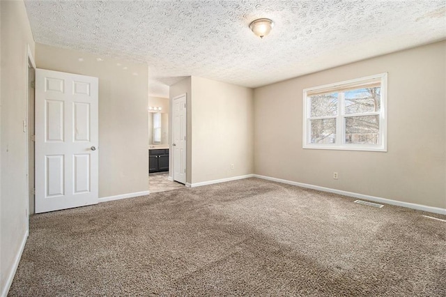 carpeted empty room featuring a textured ceiling