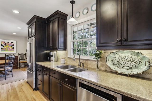 kitchen featuring dark brown cabinets, stainless steel appliances, sink, pendant lighting, and light hardwood / wood-style floors