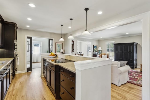 kitchen featuring pendant lighting, black electric cooktop, a kitchen island, and light hardwood / wood-style floors