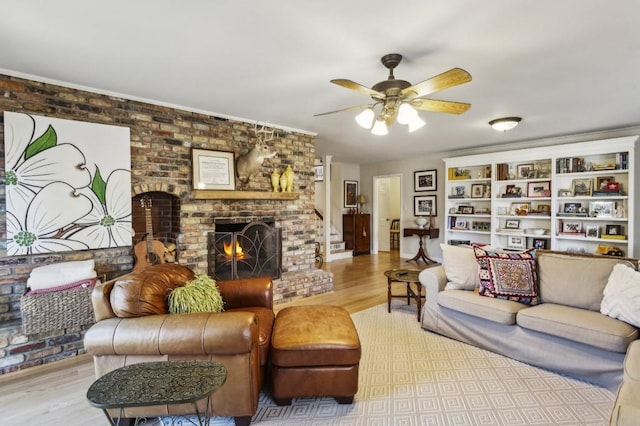 living room featuring light hardwood / wood-style floors, a brick fireplace, and ceiling fan