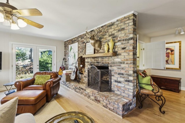 living room featuring a fireplace, french doors, light wood-type flooring, and ceiling fan