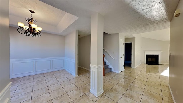 tiled spare room with a notable chandelier and a textured ceiling