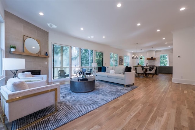 living room with a fireplace, light hardwood / wood-style flooring, and a chandelier