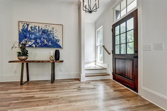 entryway featuring light hardwood / wood-style flooring, ornamental molding, and a notable chandelier