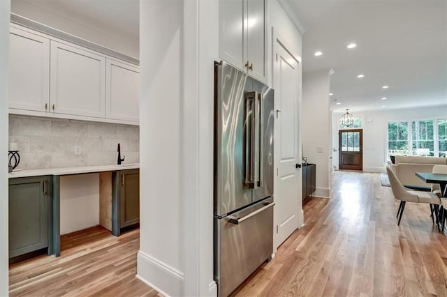 kitchen with high quality fridge, decorative backsplash, light hardwood / wood-style flooring, and white cabinets