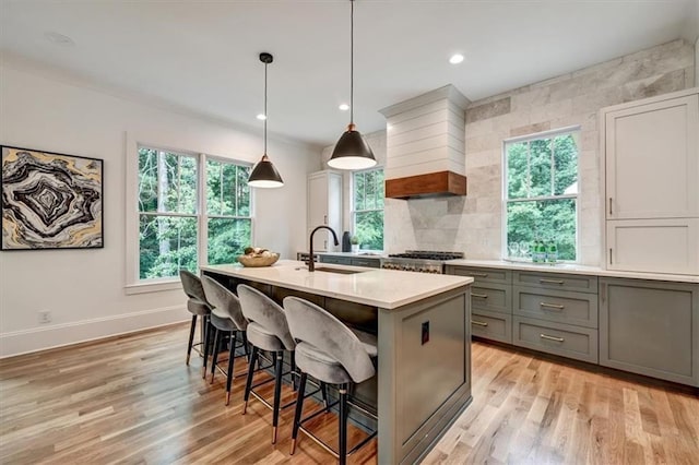 kitchen featuring sink, light wood-type flooring, hanging light fixtures, and a wealth of natural light