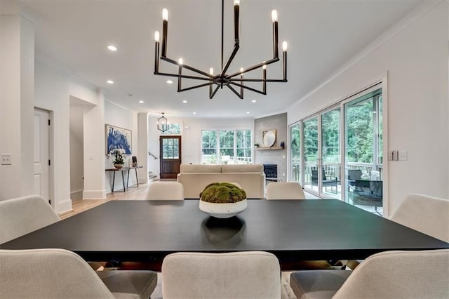 dining area featuring plenty of natural light, a large fireplace, ornamental molding, and light hardwood / wood-style flooring