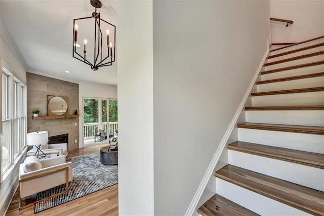 stairs with a chandelier, a fireplace, and wood-type flooring