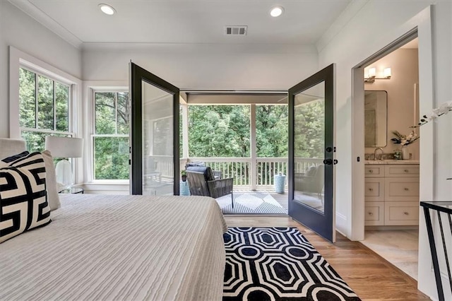 bedroom featuring access to exterior, connected bathroom, light hardwood / wood-style floors, and ornamental molding