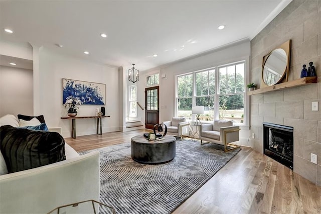 living room with a fireplace, ornamental molding, a notable chandelier, and light wood-type flooring