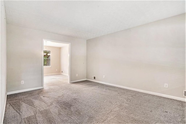 spare room featuring a textured ceiling and carpet