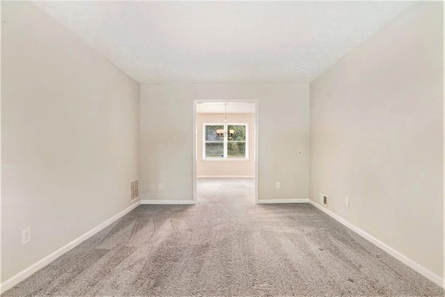 empty room with an inviting chandelier and light colored carpet