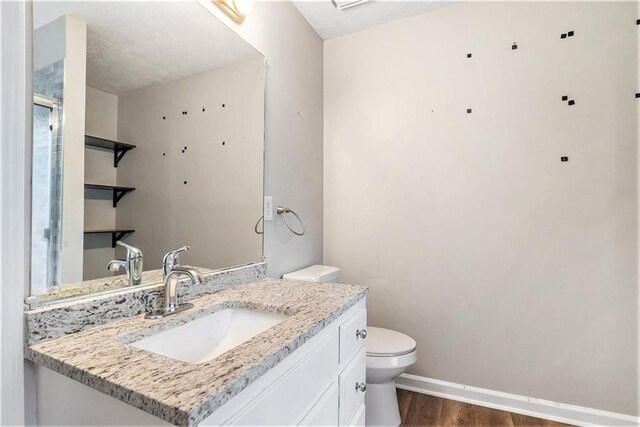 bathroom featuring vanity, toilet, hardwood / wood-style floors, and a textured ceiling