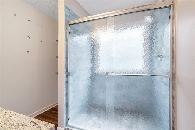 bathroom with hardwood / wood-style floors and a shower with shower door