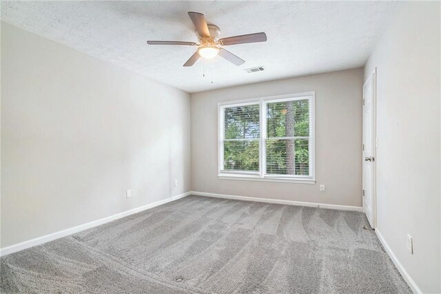 carpeted spare room featuring a textured ceiling and ceiling fan