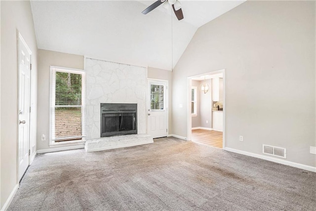 unfurnished living room featuring ceiling fan, a stone fireplace, high vaulted ceiling, and light carpet