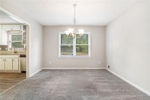 unfurnished dining area with wood-type flooring, sink, a notable chandelier, and a healthy amount of sunlight