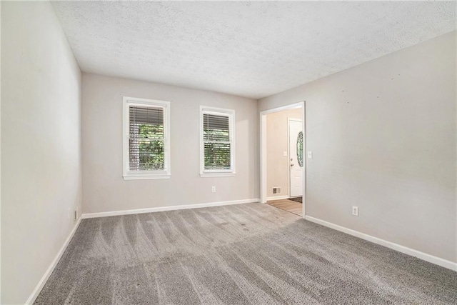 carpeted empty room featuring a textured ceiling