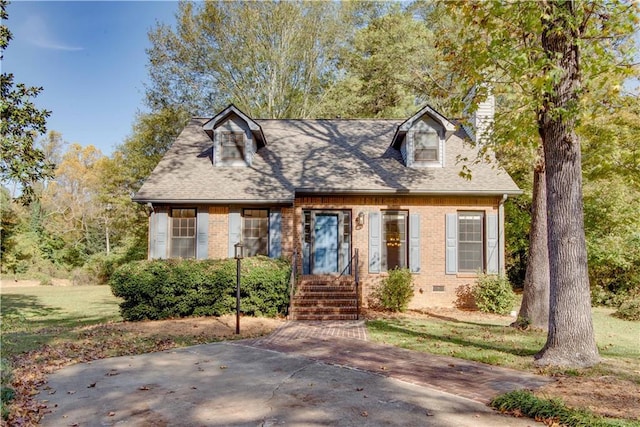 cape cod home with a shingled roof, a front yard, crawl space, and brick siding