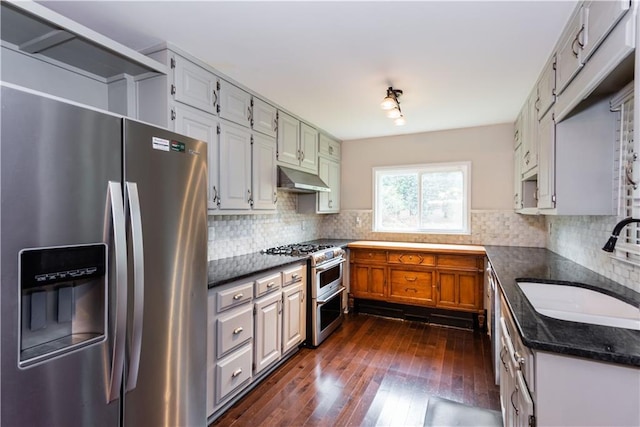 kitchen with appliances with stainless steel finishes, decorative backsplash, sink, and dark hardwood / wood-style floors