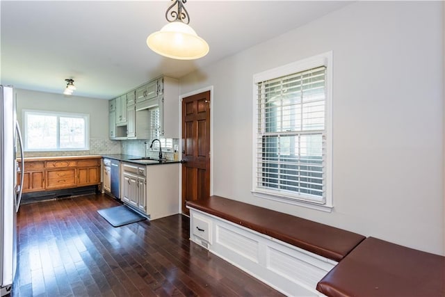 kitchen featuring appliances with stainless steel finishes, sink, pendant lighting, dark hardwood / wood-style floors, and tasteful backsplash