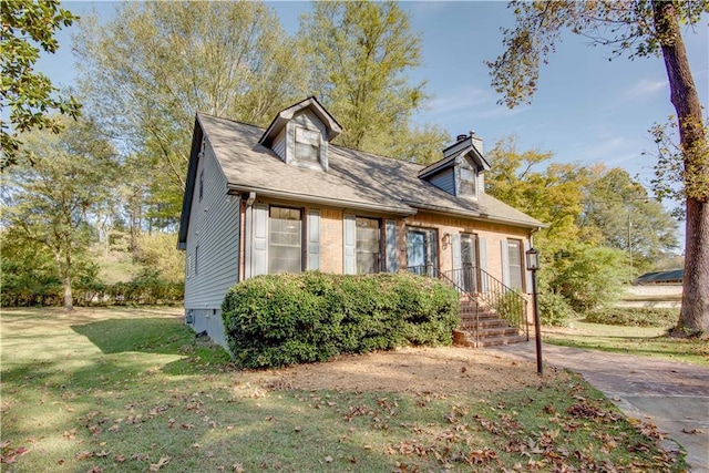 new england style home with brick siding and a front yard