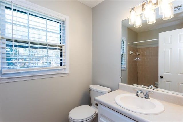 bathroom with toilet, vanity, and tiled shower