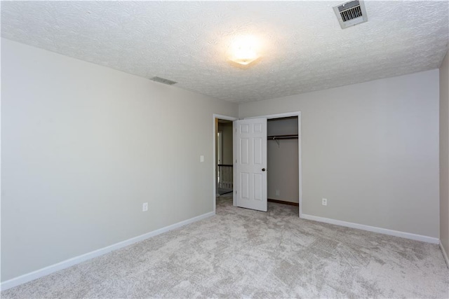 unfurnished bedroom with a textured ceiling, a closet, and light carpet