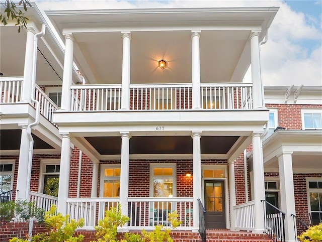 view of exterior entry with a porch and brick siding