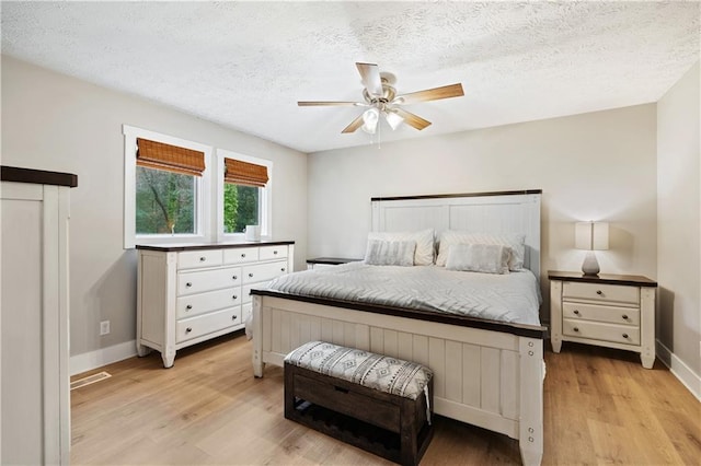 bedroom with light wood finished floors, a textured ceiling, baseboards, and a ceiling fan