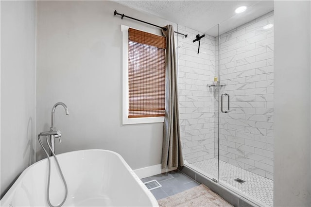 bathroom with visible vents, a freestanding bath, a stall shower, a textured ceiling, and baseboards