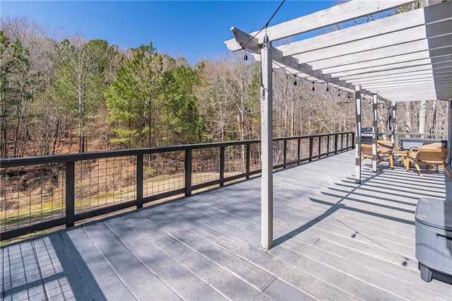 wooden deck with a wooded view and a pergola