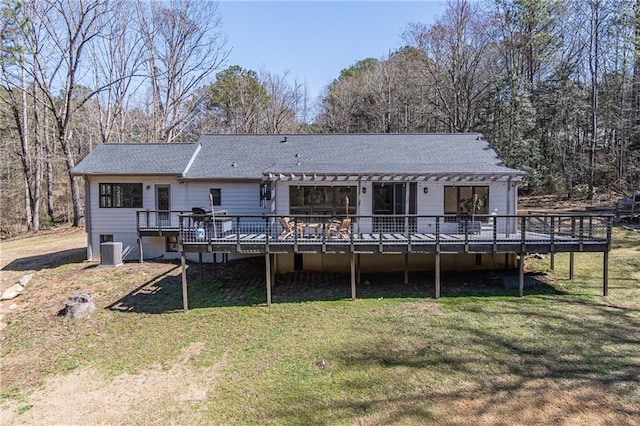 rear view of property featuring a deck, central air condition unit, a shingled roof, a yard, and a pergola