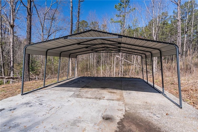 view of car parking featuring a carport, driveway, and a wooded view