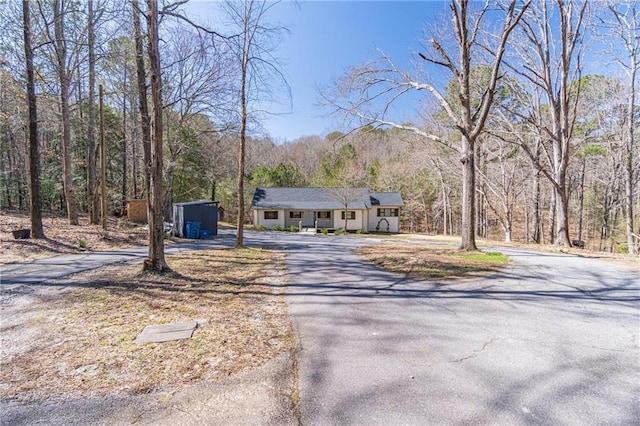 view of front of home featuring driveway and a wooded view