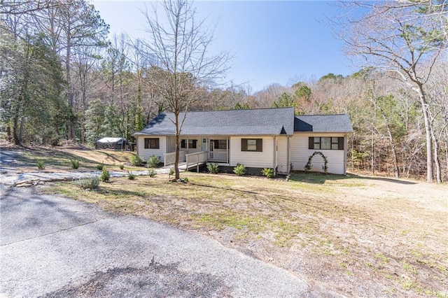 ranch-style home with covered porch and a view of trees