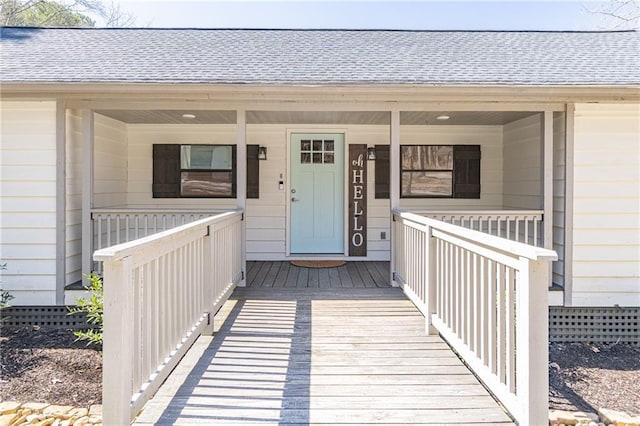 property entrance featuring covered porch and a shingled roof