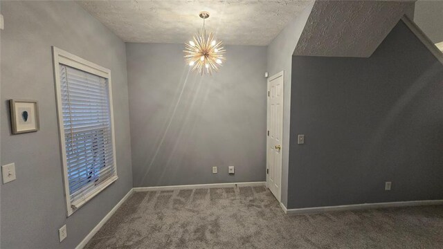 spare room featuring carpet, a textured ceiling, and a notable chandelier