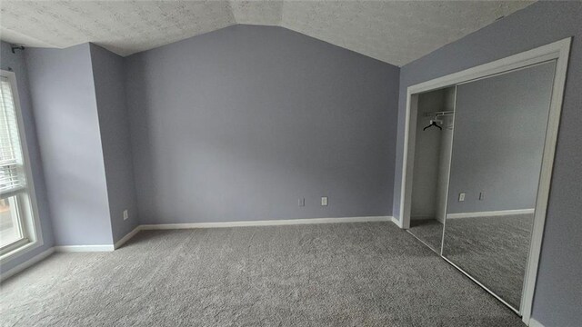 unfurnished bedroom with lofted ceiling, carpet, and a textured ceiling