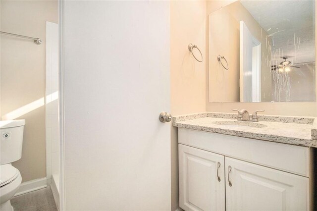 bathroom with walk in shower, ceiling fan, vanity, and toilet