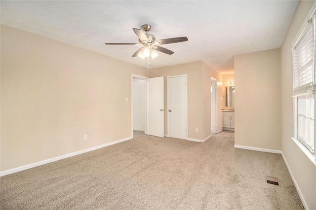 spare room featuring ceiling fan, light colored carpet, and a healthy amount of sunlight