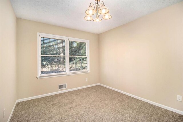 empty room featuring carpet floors and a notable chandelier