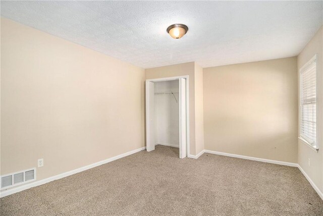 unfurnished bedroom featuring carpet, a textured ceiling, and a closet