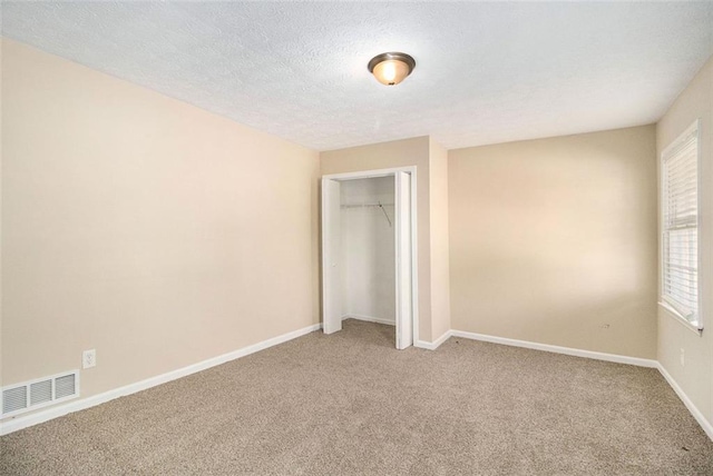 unfurnished bedroom featuring a textured ceiling, carpet floors, and a closet