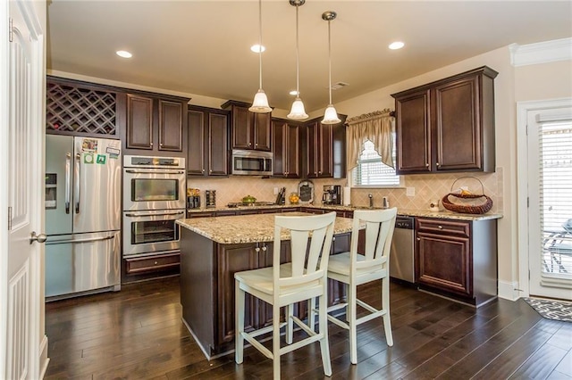 kitchen with a wealth of natural light, stainless steel appliances, dark hardwood / wood-style floors, and hanging light fixtures